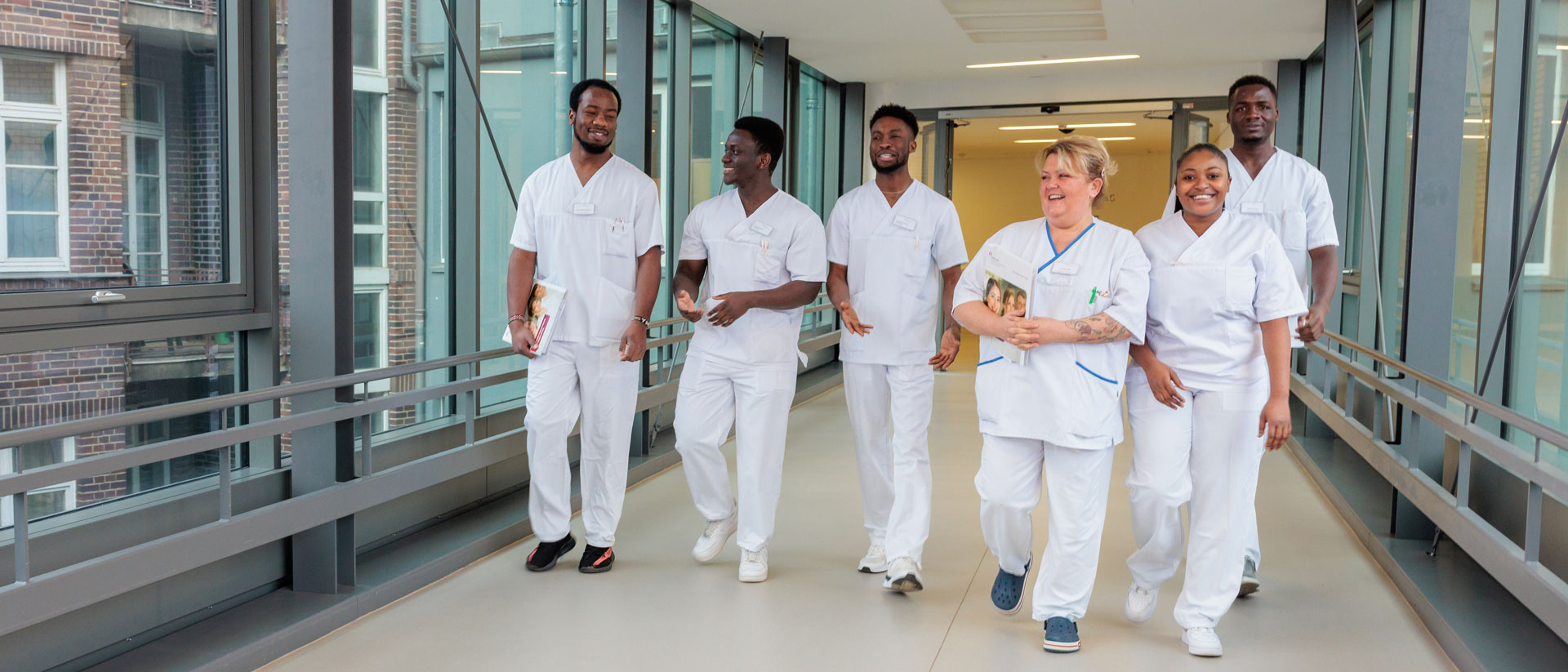 Eine Gruppe von Pflegekräften geht im Krankenhaus gemeinsam über einen Flur. 