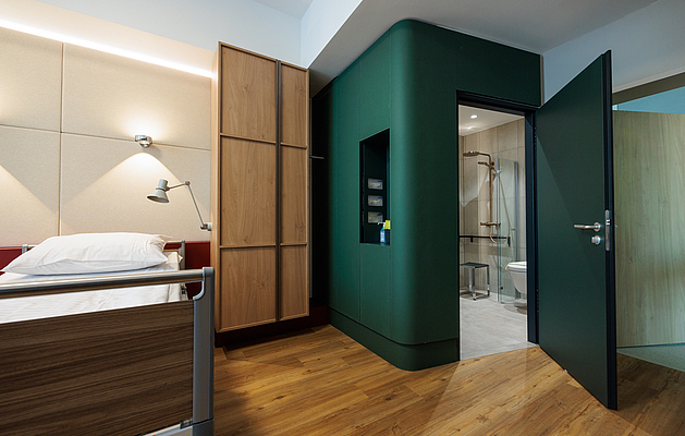 Ein modernes Patientenzimmer mit einem eigenen Badezimmer. 