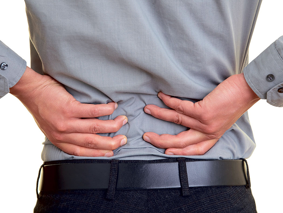 Das Bild zeigt einen Mann von hinten, der Schmerzen am unteren Rücken hat.