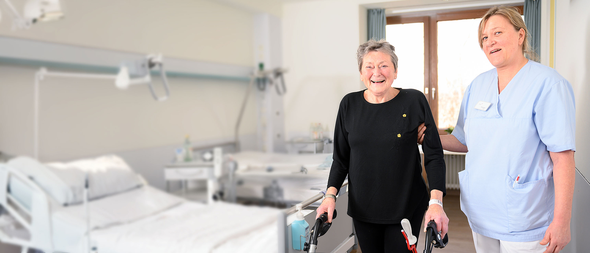 Bild zeigt eine Pflegerin, die eine ältere Patientin am Rollator begleitet