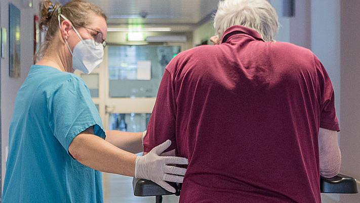 Eine Therapeutin begleitet einen älteren Patienten auf der Station im Zentrum für Medizin im Alter im DIAKOVERE Henriettenstift Kirchrode
