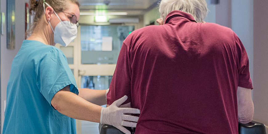 Eine Therapeutin begleitet einen älteren Patienten auf der Station im Zentrum für Medizin im Alter im DIAKOVERE Henriettenstift Kirchrode